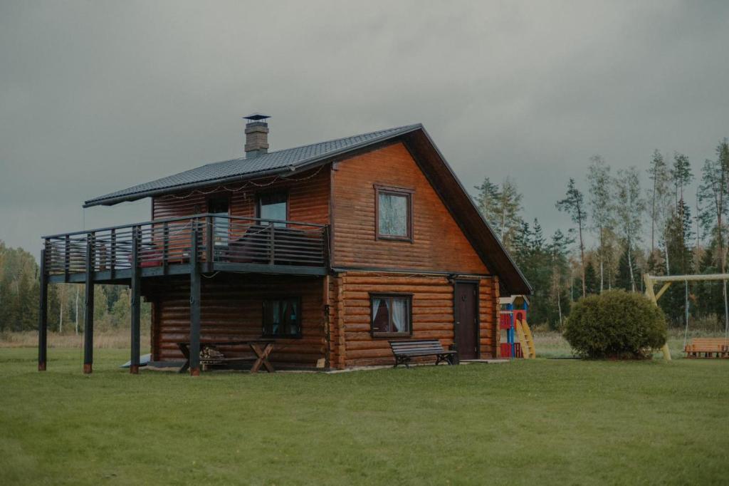 a log cabin with a porch and a balcony at Atpūtas vieta Jaunkārkliņi 
