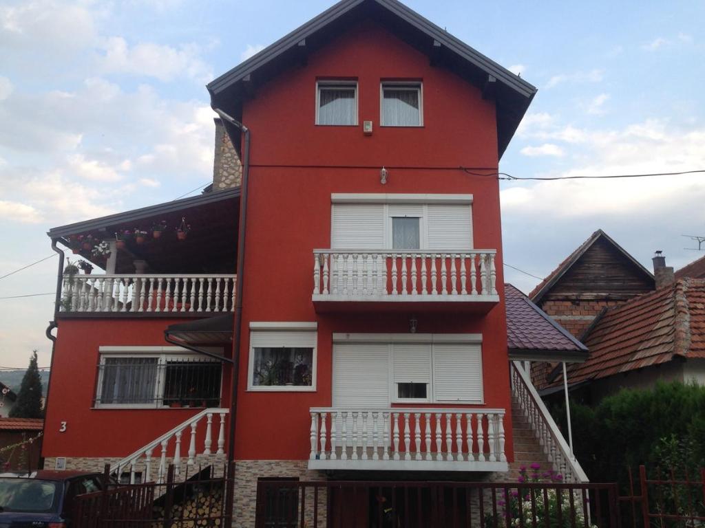 a red house with white balconies on the side of it at Apartment Red House in Visoko