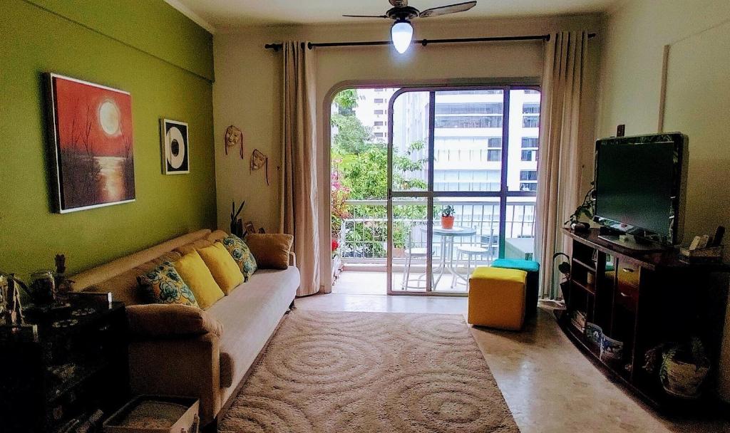 un salon avec un canapé et une télévision dans l'établissement Apto PITANGUEIRAS SACADA-5Min Praia 1 vaga SERV PRAIA, à Guarujá