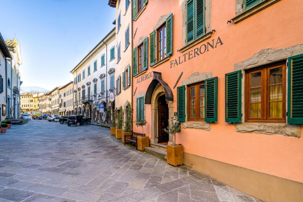 a street with a building with green shutters at Albergo Falterona in Stia