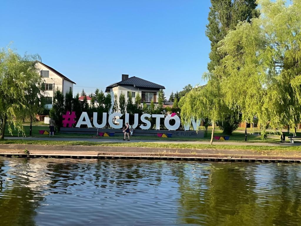 a sign in a park next to a body of water at Augustòw Centre 1-Bedroom Comfort and Leisure. in Augustów