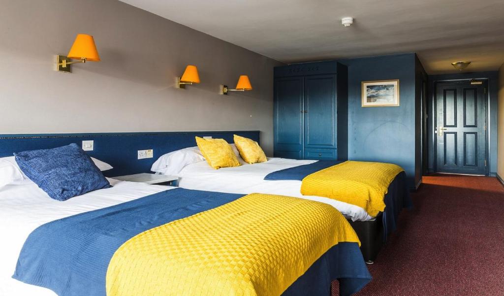 Habitación de hotel con 2 camas de color amarillo y azul en The Donard Hotel, en Newcastle