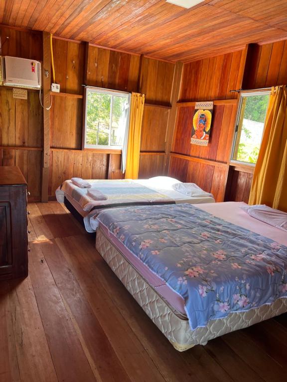 1 Schlafzimmer mit 2 Betten in einem Holzzimmer in der Unterkunft Casa Encanto in Manacapuru