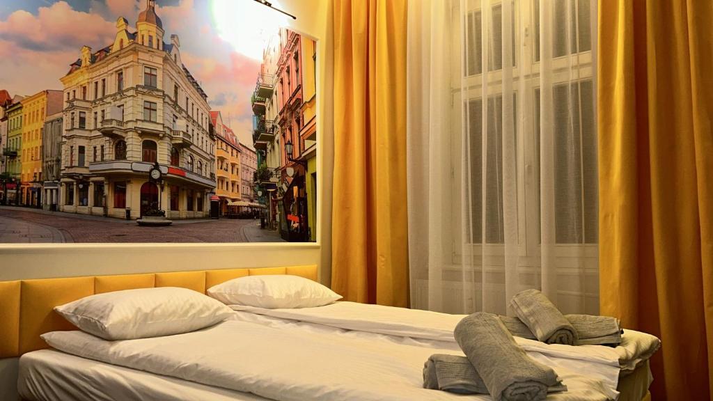 2 Betten vor einem Fenster mit einem Bild einer Stadt in der Unterkunft Quick Trip Apartments Toruń in Toruń