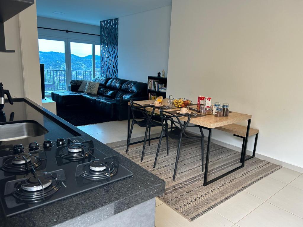 a kitchen and living room with a table and a stove at Apartamento na Montanha em Campos in Campos do Jordão