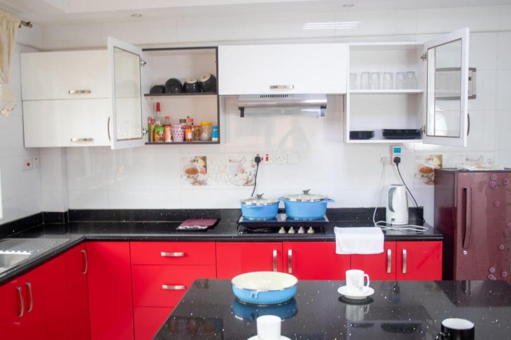 a kitchen with red cabinets and blue bowls on the counter at 4bedroom westlands raphta Nairobi in Nairobi