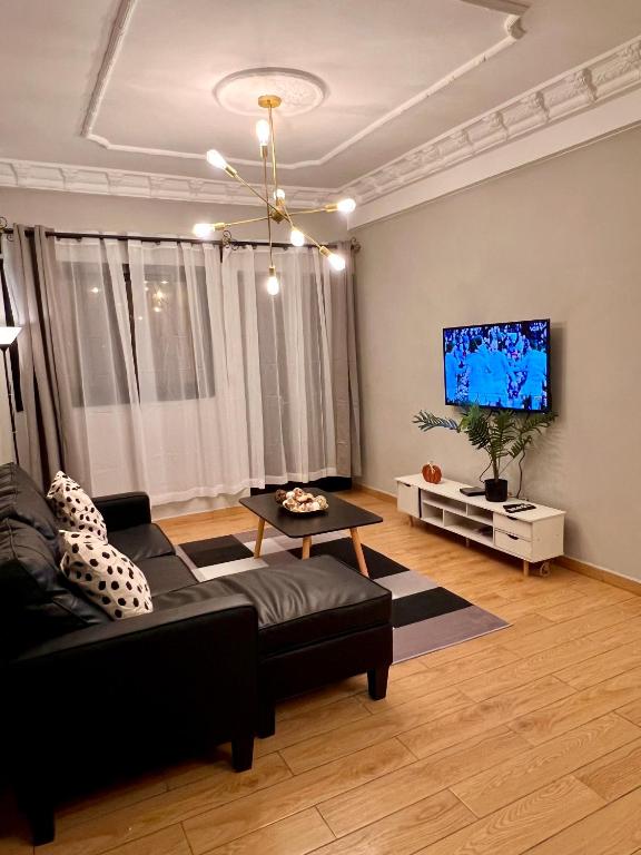 a living room with a couch and a flat screen tv at Residence Ethan Nji - Chic urban in Yaoundé