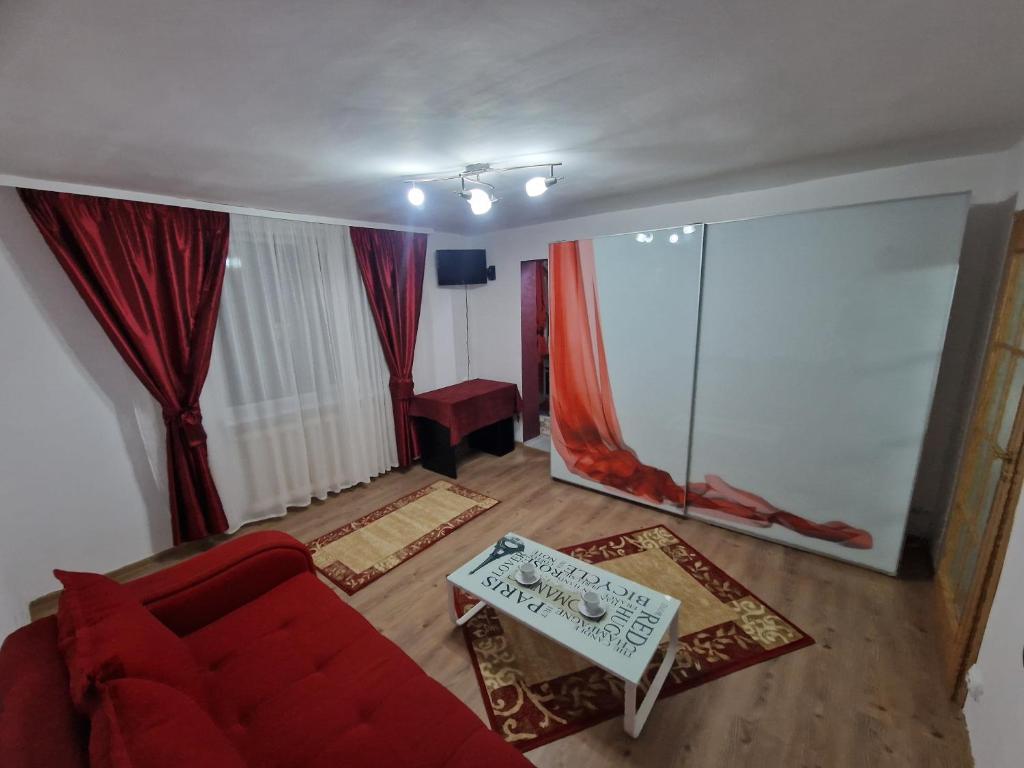 a living room with a red couch and a table at Micro-apartament NADEVA in Suceava