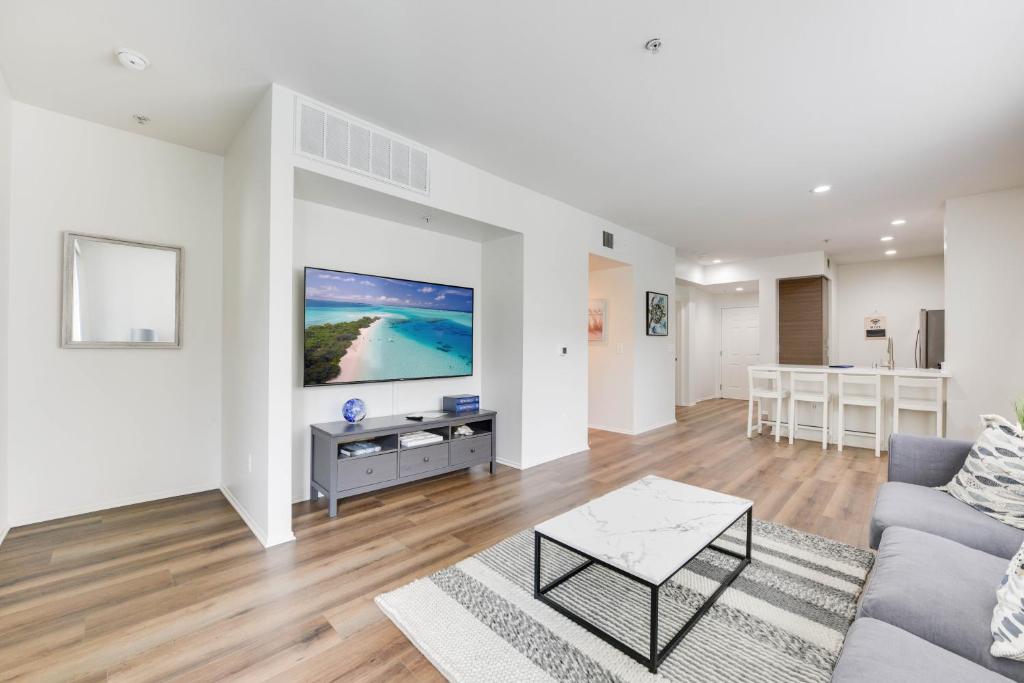 a living room with a couch and a tv on a wall at The Electric Blue Abode with a Gorgeous Pool View in Los Angeles