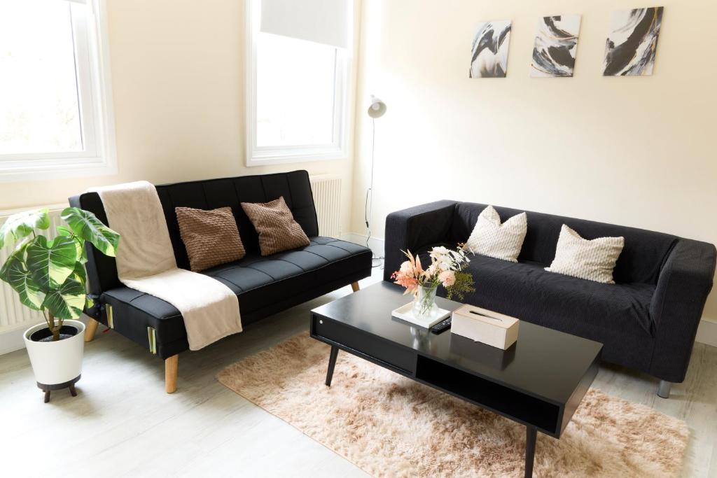 a living room with a black couch and a coffee table at Central London Flat, Stylish 1BR near Shoreditch in London