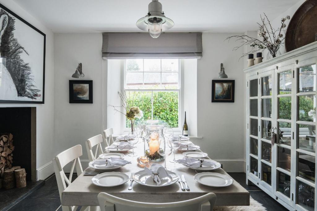 un comedor con una mesa larga con platos blancos en Devon Farmhouse en Kingsbridge