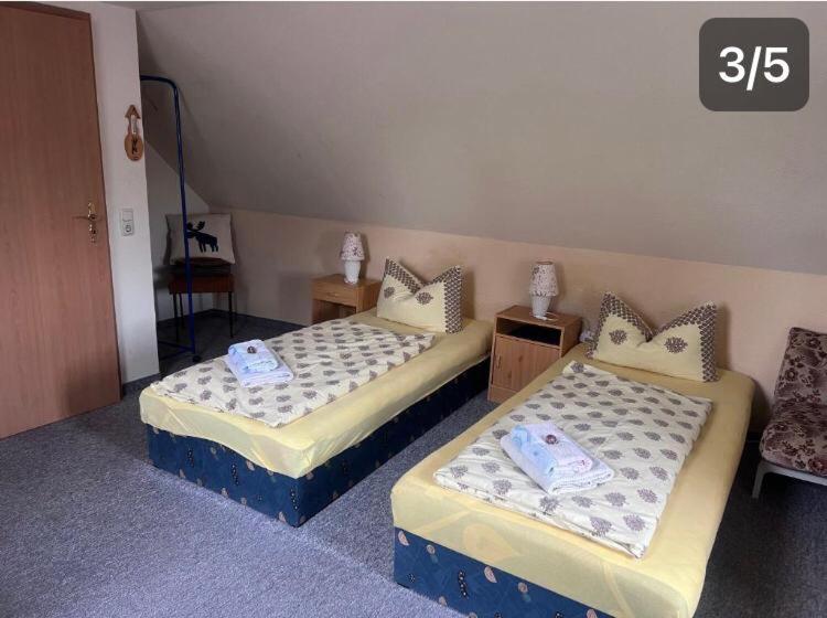 een kamer met 2 bedden en een stoel bij Doppelzimmer Obergeschoss in Münchenbernsdorf