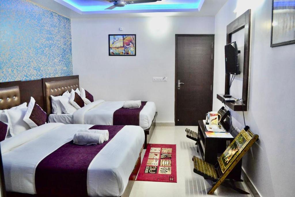 a hotel room with two beds and a television at Hotel Premium Blossom Rooms in Agra