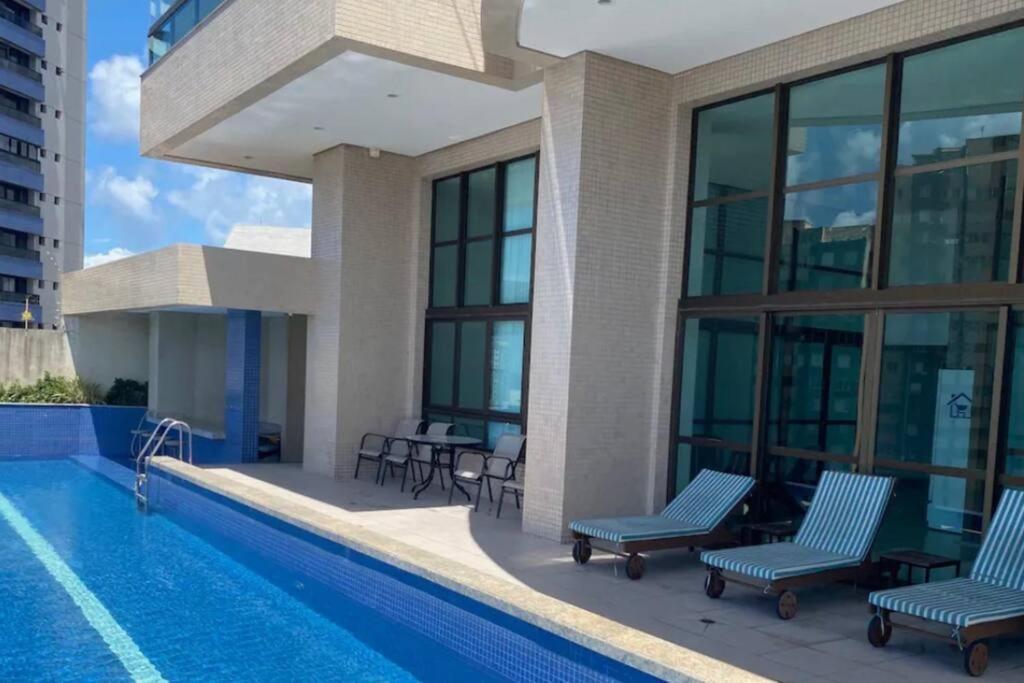 uma piscina com cadeiras ao lado de um edifício em Apartamento Total Vista do Mar. em Salvador