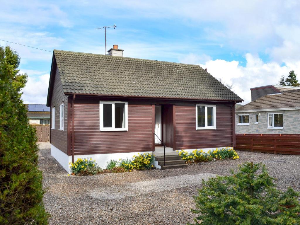 a small brown house with a garage at Cedar Cottage - Uk32633 in Grantown on Spey