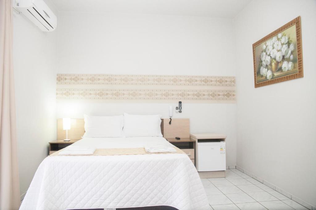 a white bedroom with a bed and a table at Hotel Grezelle in Santa Bárbara