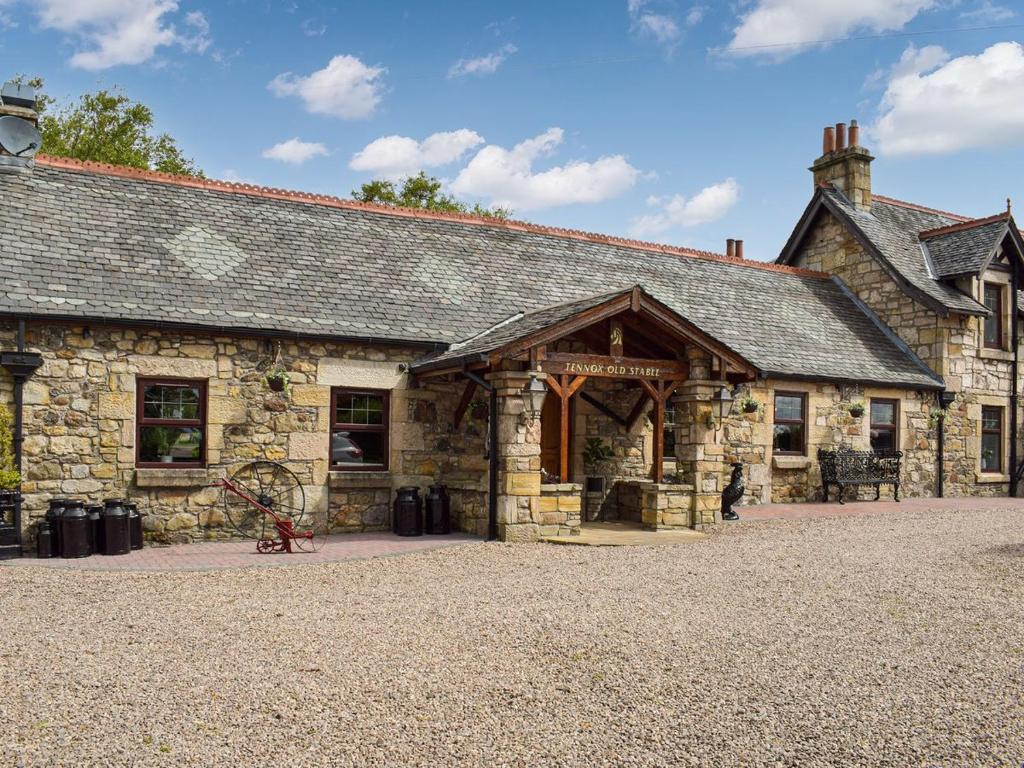 an old stone building with a large building at Tennox Stables - Uk39975 in Kilbirnie