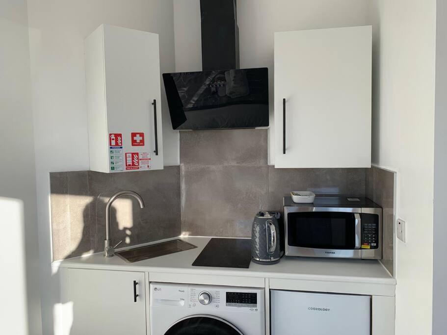eine Küche mit einer Spüle und einer Mikrowelle in der Unterkunft Annex B, a Studio flat in London in Carshalton