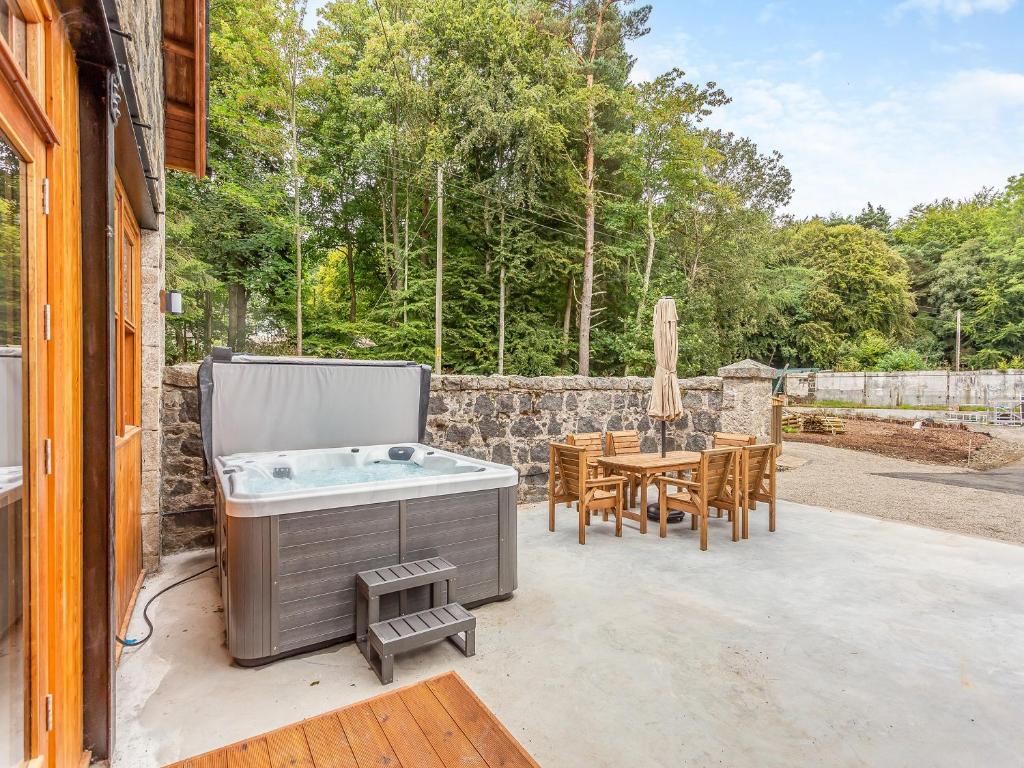 a hot tub on a patio with a table and chairs at Gardeners Cottage in Huntly
