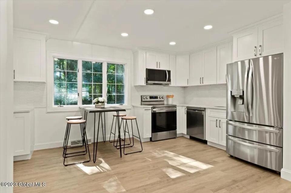 uma cozinha com armários brancos e um frigorífico de aço inoxidável em SPAC Trac Oasis em Saratoga Springs