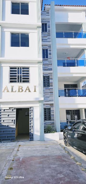 a white building with a car parked in front of it at Casa familiar in San Pedro de Macorís