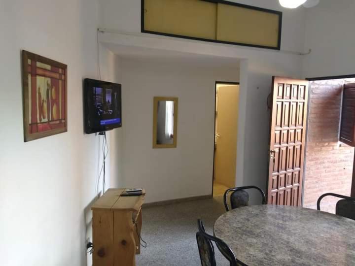 Habitación con mesa y TV en la pared. en Dpto Villa Carlos Paz en Villa Carlos Paz