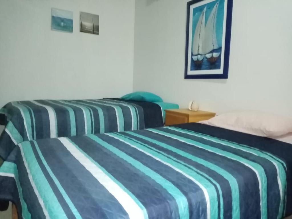 two beds in a hotel room with a striped bedspread at Hospedaje La Estancia Punta Sal in La Bocana