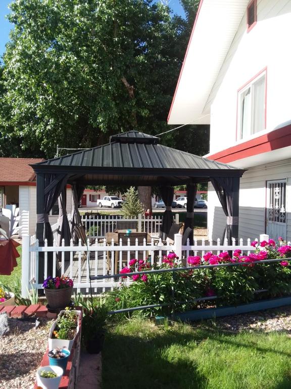 a black gazebo with a white fence and flowers at Travel Inn Motel in Canon City