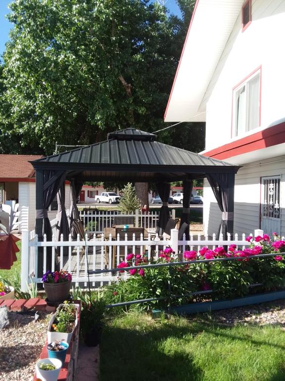 un cenador negro con una valla blanca y flores en Travel Inn Motel, en Canon City