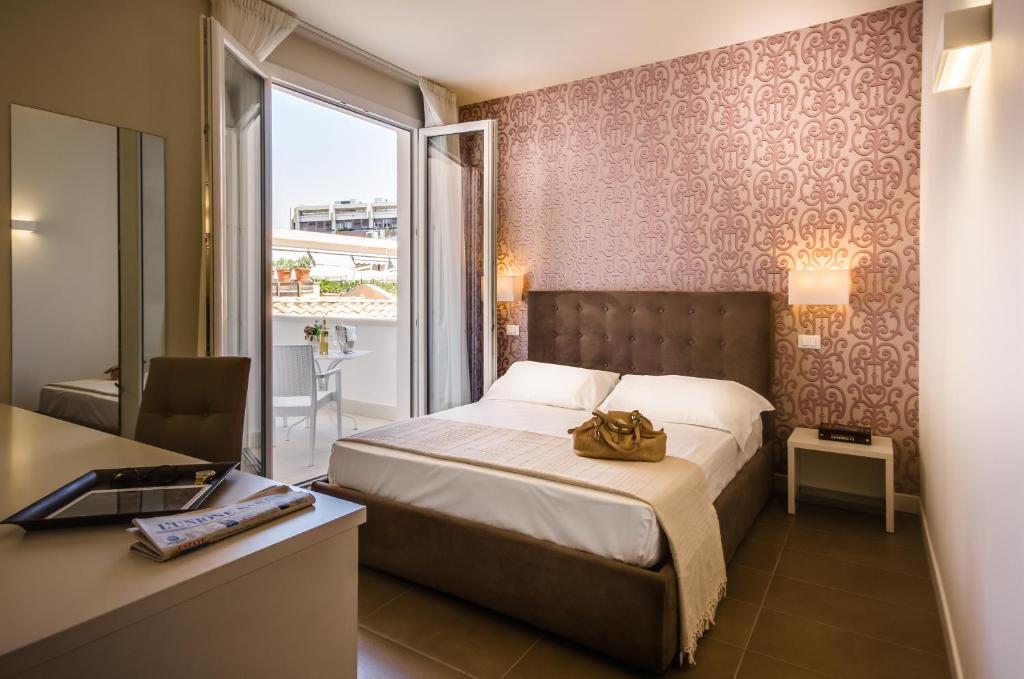 a bedroom with a bed and a desk and a window at Il Gallo Bianco in Cagliari