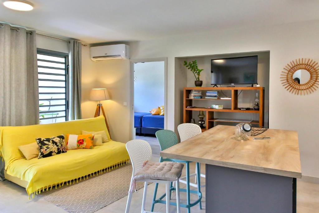 - un salon avec un canapé jaune et une table dans l'établissement Charmant Appartement Topaze, à Papeete