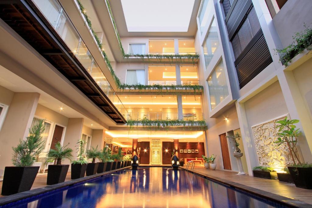a lobby with a swimming pool in a building at Ohana Hotel Kuta in Kuta