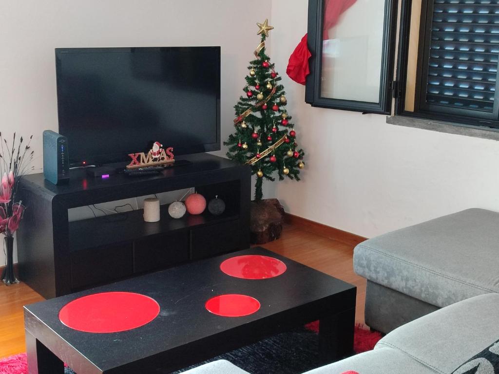 a living room with a christmas tree and a tv at Delfina`s House in Machico