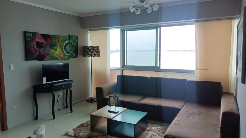 uma sala de estar com um sofá e uma televisão em 2 habitaciónes vista al río 102 em Guayaquil