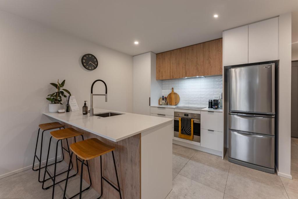 uma cozinha com um frigorífico de aço inoxidável e bancos em Urban Nest - Entire Townhouse and Free Parking em Christchurch