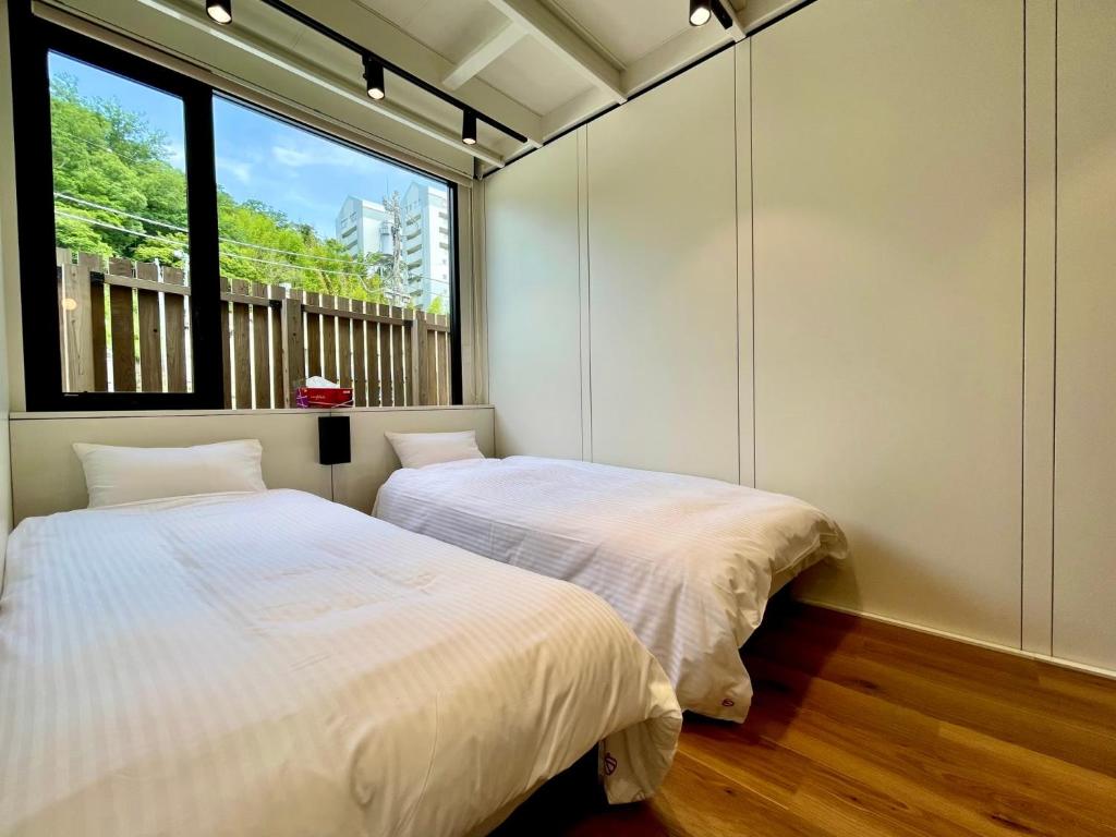 two beds in a room with a window at さかなやステイ in Kona