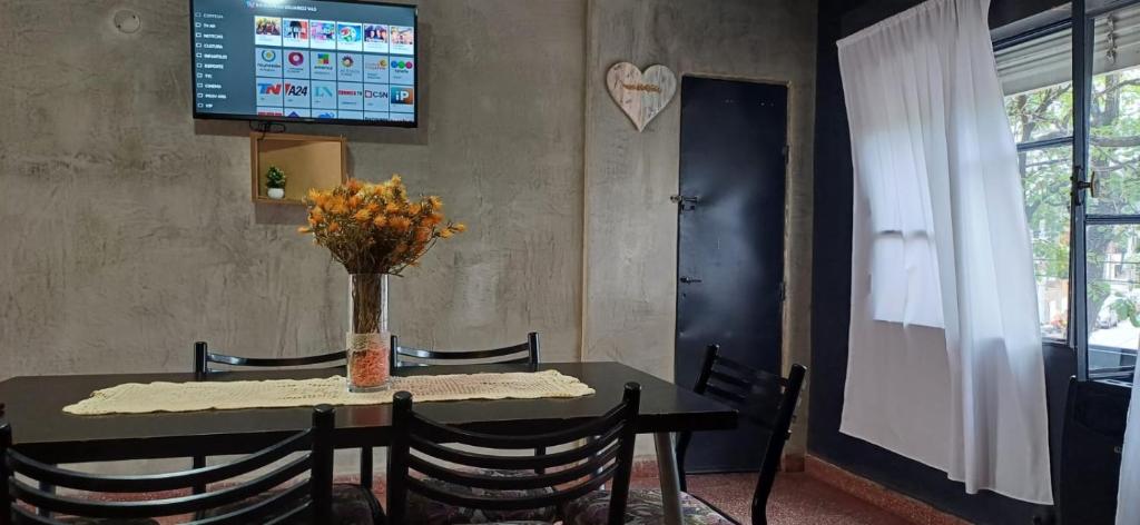 una mesa de comedor con un jarrón de flores. en Departamento Céntrico en Termas de Río Hondo