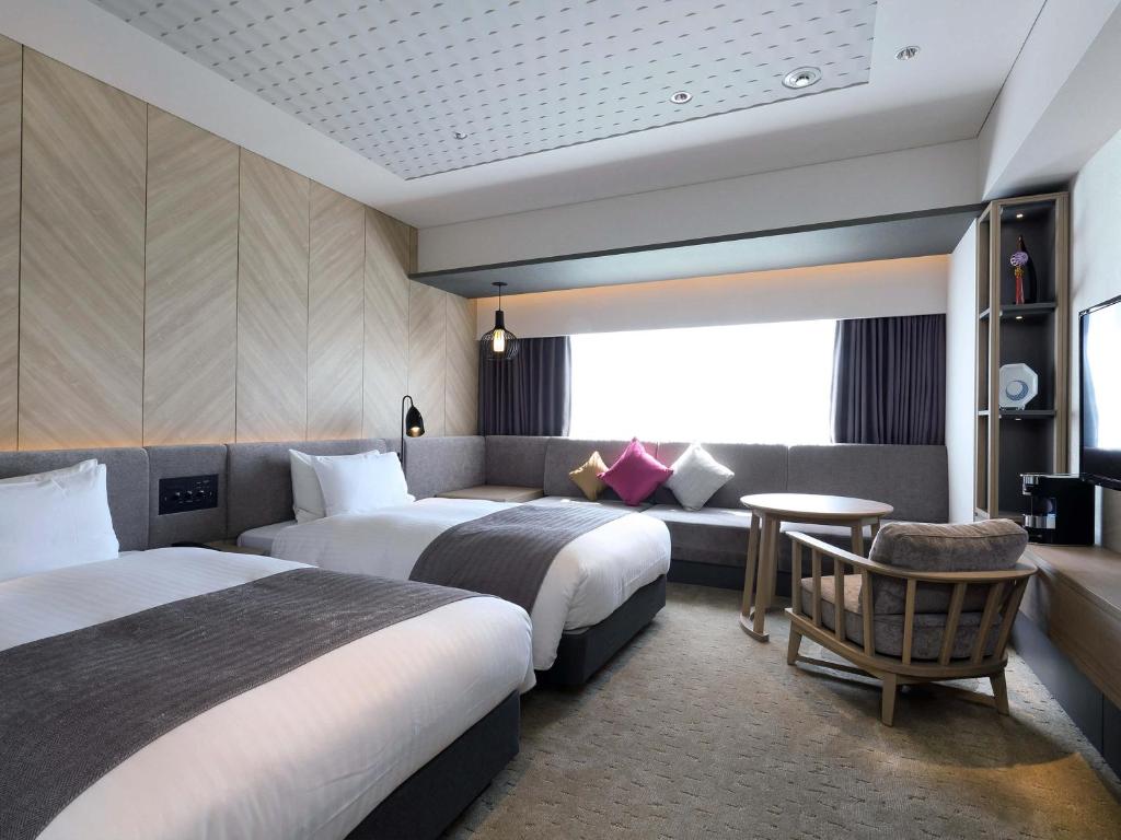 a hotel room with two beds and a couch at Solaria Nishitetsu Hotel Fukuoka in Fukuoka