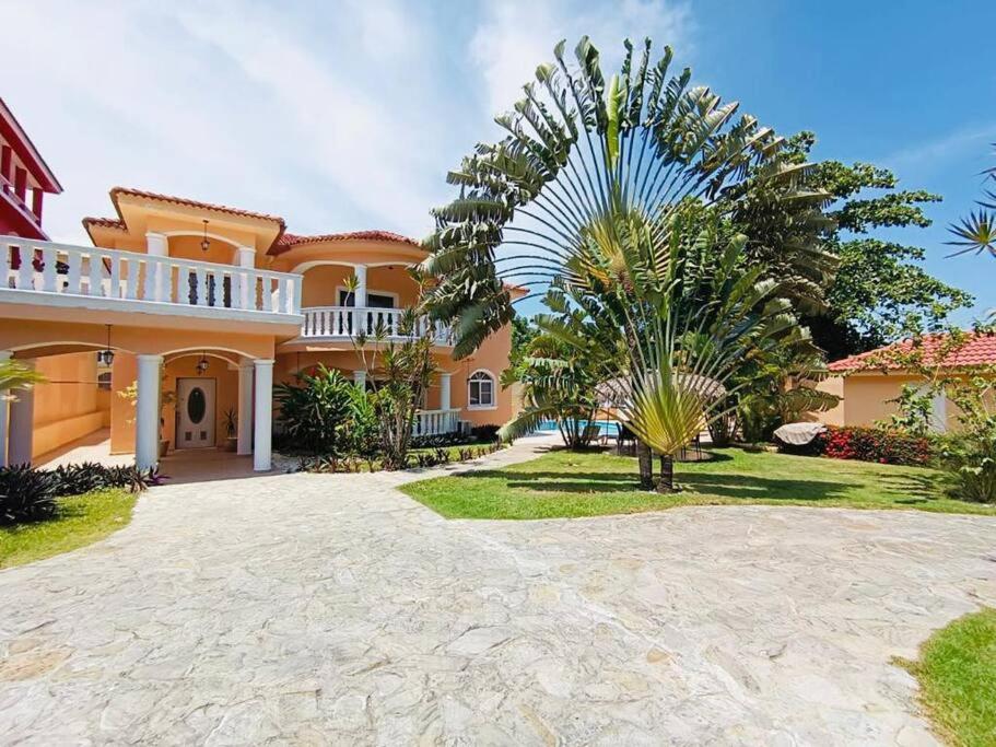 a large house with a palm tree in front of it at Luxury Villa Classic style - 7 min. from the beach in San Felipe de Puerto Plata