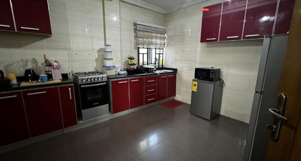 a small kitchen with red cabinets and a stove at Haatso House in Accra