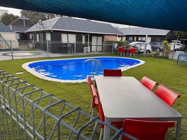 a table and chairs in front of a swimming pool at ASURE Kapiti Court Motel in Paraparaumu Beach