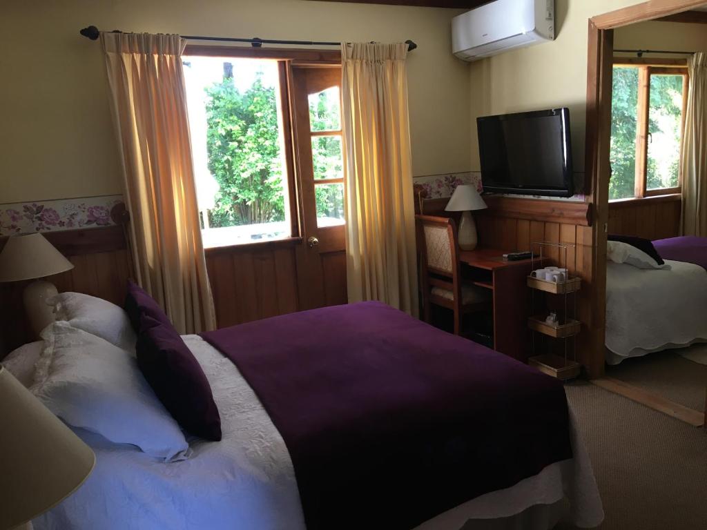 a bedroom with a bed and a flat screen tv at Merken Bed & Breakfast in Villarrica