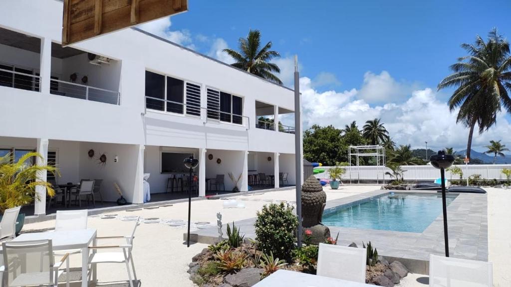 an exterior view of a building with a swimming pool at Pension Irivai appartement PUATOU 1 chambre bord de mer in Uturoa