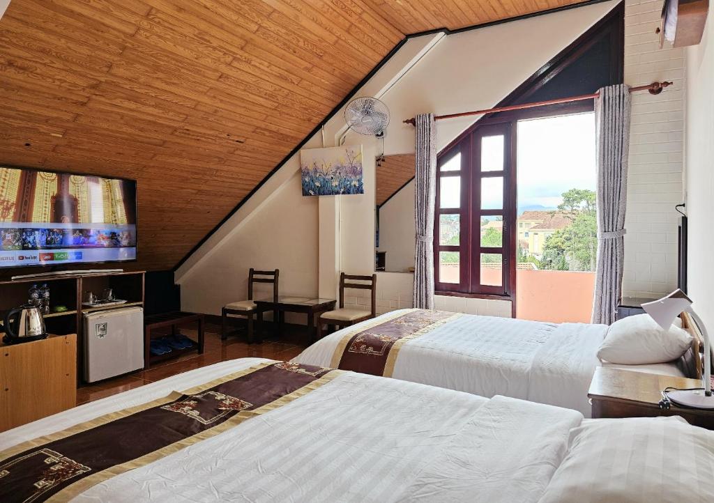 a bedroom with two beds and a large window at Villa Pink House in Da Lat