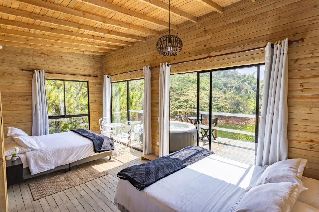 1 dormitorio con 2 camas y balcón con bañera en Cabañas Refugio Himalaya, en Guatapé