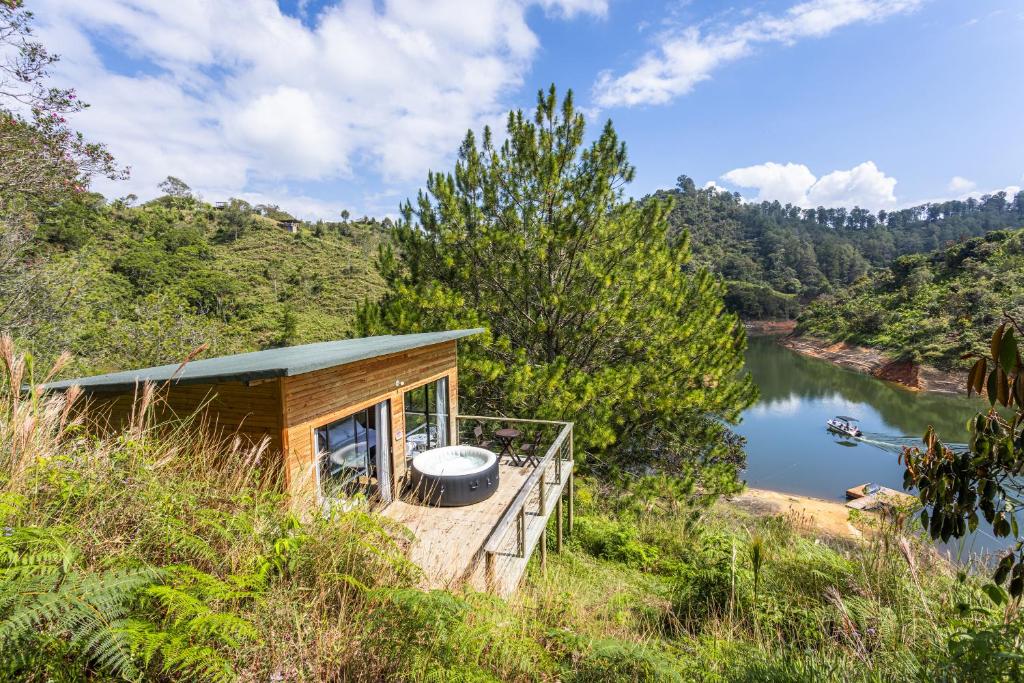 una cabaña en una colina junto a un cuerpo de agua en Cabañas Refugio Himalaya, en Guatapé
