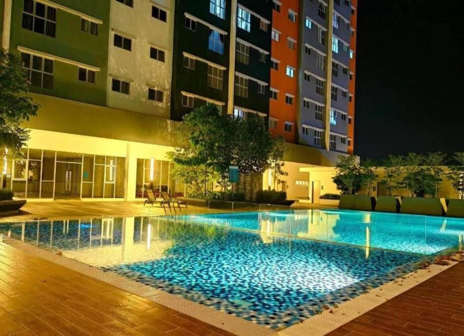 - une piscine en face d'un bâtiment la nuit dans l'établissement AMFA Homestay the best (2bedroom), à Sepang