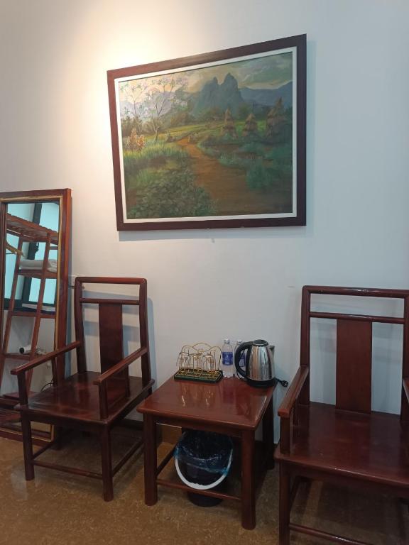 a room with two tables and two chairs and a painting at An Homestay & Hostel Motorbikes & Tours in Cao Bằng