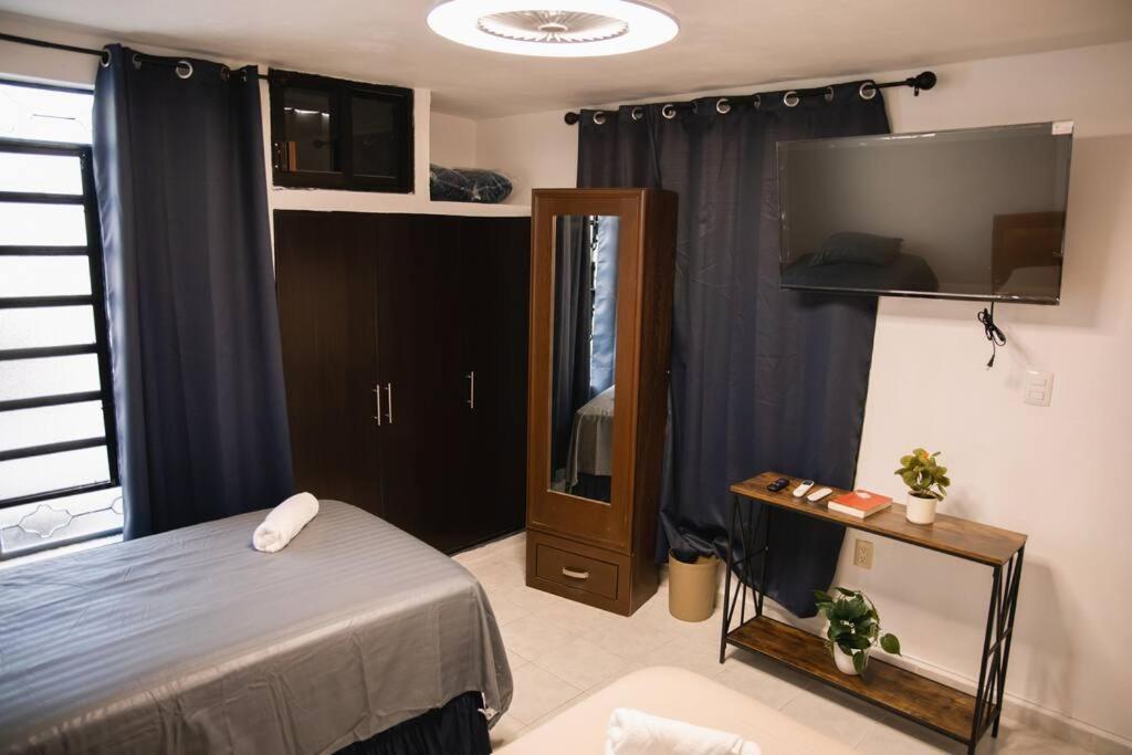 ein Schlafzimmer mit einem Bett und einem Spiegel sowie einem TV in der Unterkunft Departamento Villanueva 2. Depto. en Chetumal in Chetumal