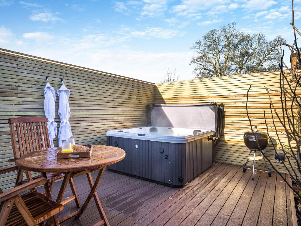 a hot tub on a deck with a wooden table at Peartree Cottage - Uk45496 